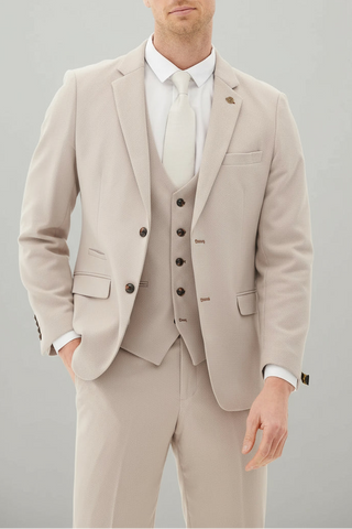 Man wearing a beige suit with a white shirt on a gray background